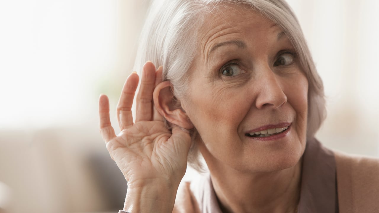 Senior Caucasian woman cupping her ear to listen