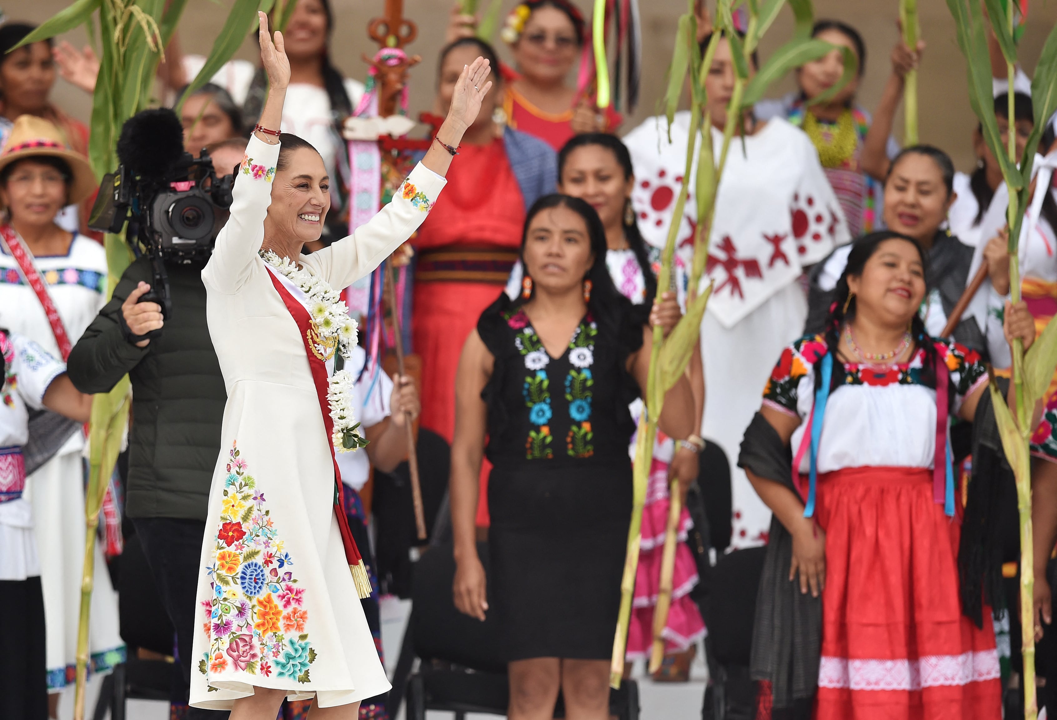 Claudia Sheinbaum (izq.), saluda a sus simpatizantes durante una ceremonia en la que recibe un bastón ceremonial de manos de indígenas en el Zócalo de la Ciudad de México el 1 de octubre de 2024. La presidenta mexicana, Claudia Sheinbaum, lució un vestido morado con bordados indígenas en su primer encuentro con Donald Trump durante el sorteo del Mundial de 2026, una elección considerada un símbolo del poder femenino.