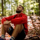 Retrato de joven relajado con auriculares bluetooth en el bosque