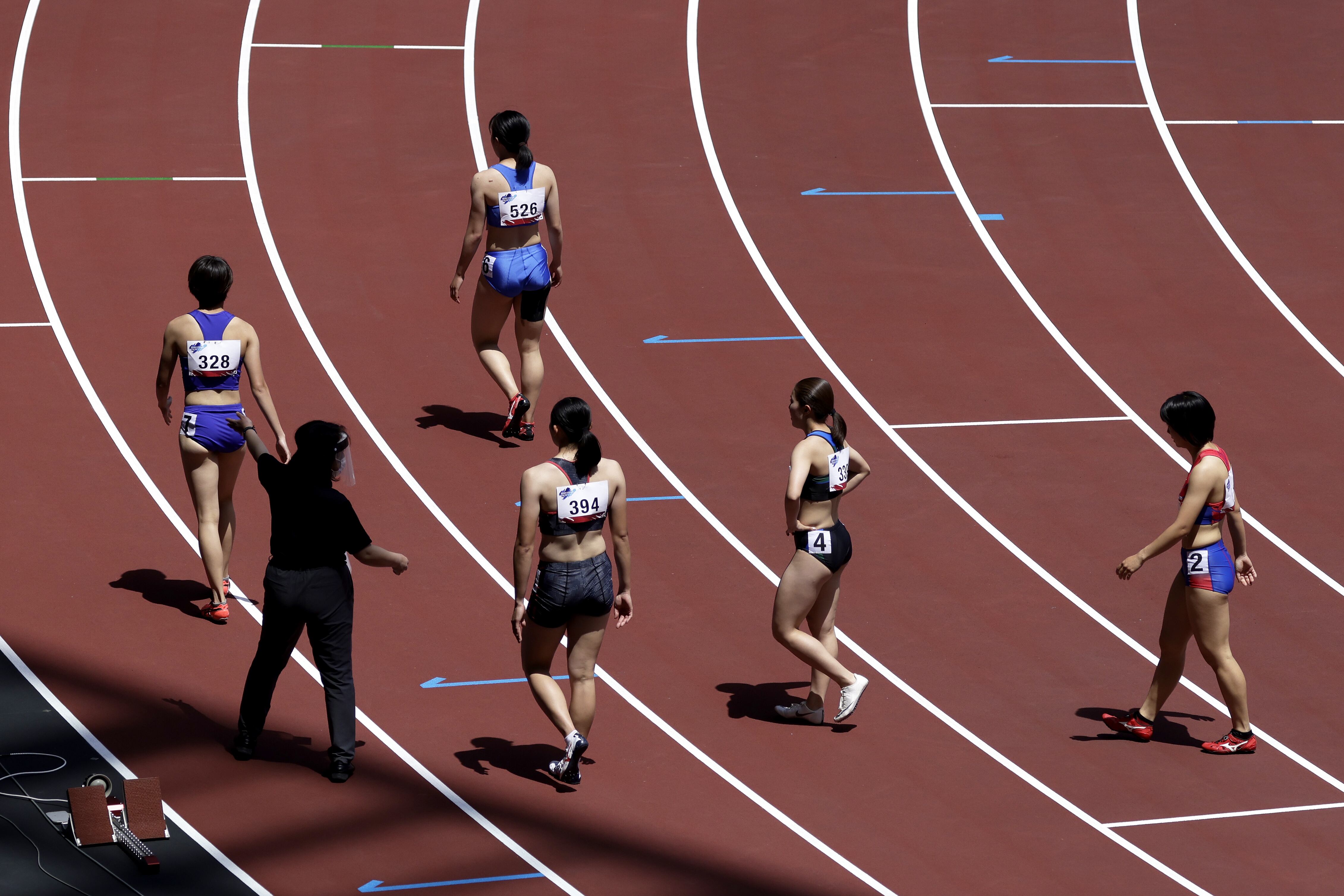 Un miembro del personal que lleva una máscara protectora y un protector facial escolta a los atletas durante un evento de prueba de atletismo para los Juegos Olímpicos de Tokio 2020 en el Estadio Nacional de Tokio, Japón, el domingo 9 de mayo de 2021.El primer ministro japonés, Yoshihide Suga, extendió el estado de emergencia. que cubre Tokio y lo expandió a dos regiones más afectadas por el aumento de casos de virus, en un intento de detener las infecciones antes de que la capital albergue los Juegos Olímpicos en menos de tres meses. Fotógrafo: Kiyoshi Ota / Bloomberg a través de Getty Images