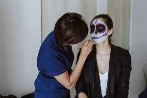 Mujer haciendo maquillaje de catrina.