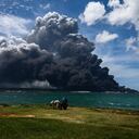 Las personas en un carro de caballos miran el humo negro del incendio masivo en un depósito de combustible en Matanzas, Cuba, el 8 de agosto de 2022. - Helicópteros se apresuraron a contener un incendio de varios días que derribó un tercer tanque en un depósito de combustible el lunes mientras continuaba la búsqueda de 16 bomberos desaparecidos. (Foto de YAMIL LAGE / AFP)