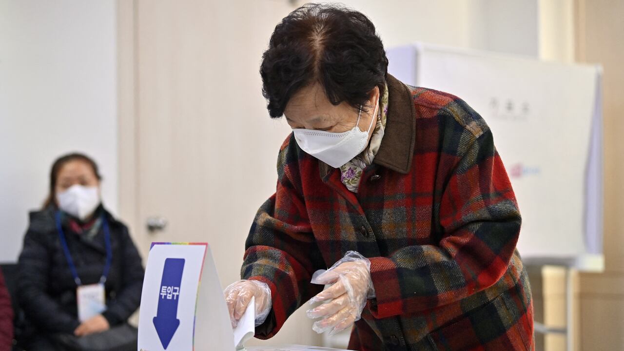 Una mujer emite su voto en las elecciones presidenciales en un colegio electoral en Seúl el 9 de marzo de 2022. (Photo by Jung Yeon-je / AFP)