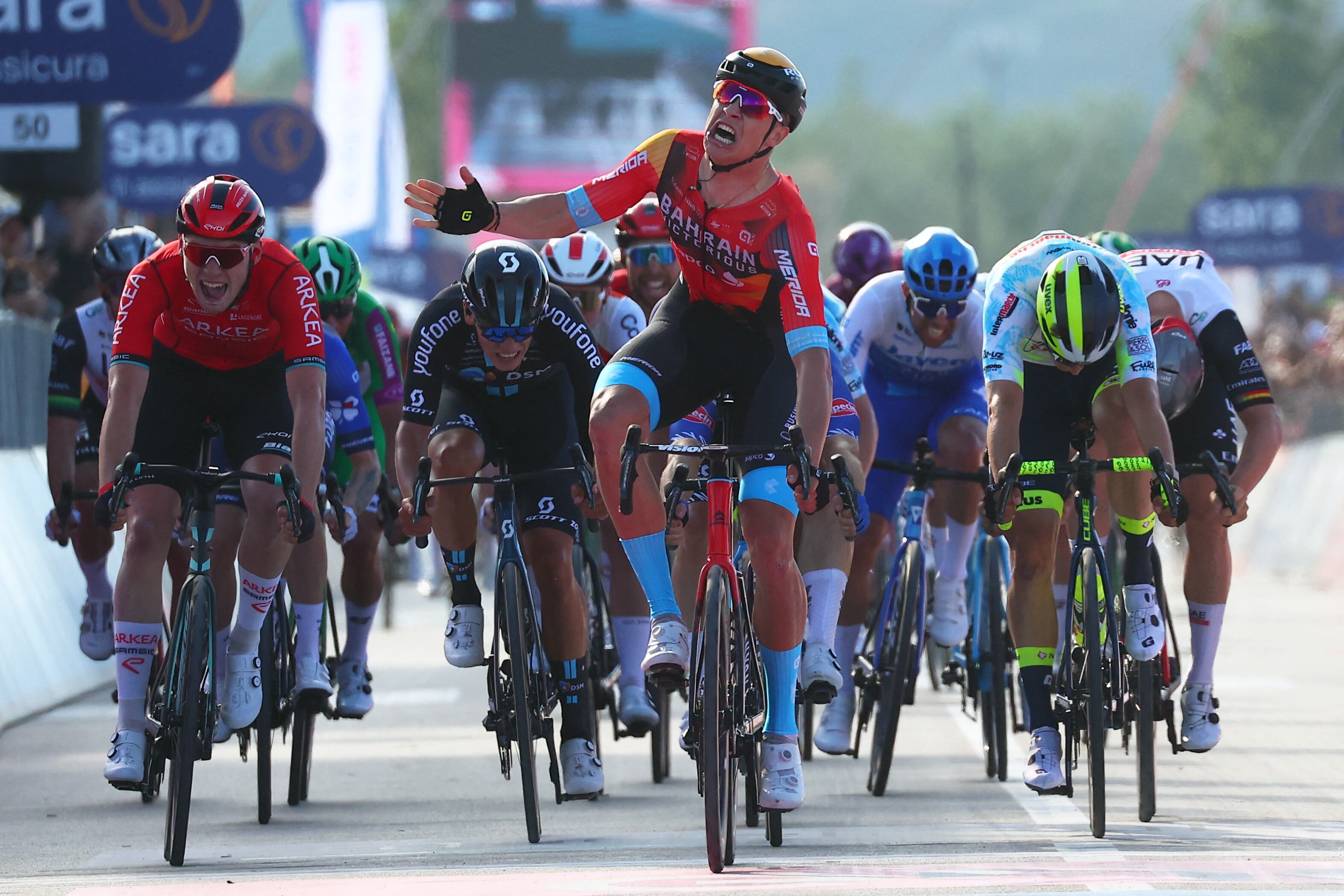 Bahrain - Victorious's Italian rider Jonathan Milan (C) celebrates as he crosses the finish line to win the second stage of the Giro d'Italia 2023 cycling race, 202 km between Teramo and San Salvo, on May 7, 2023. (Photo by Luca Bettini / AFP)