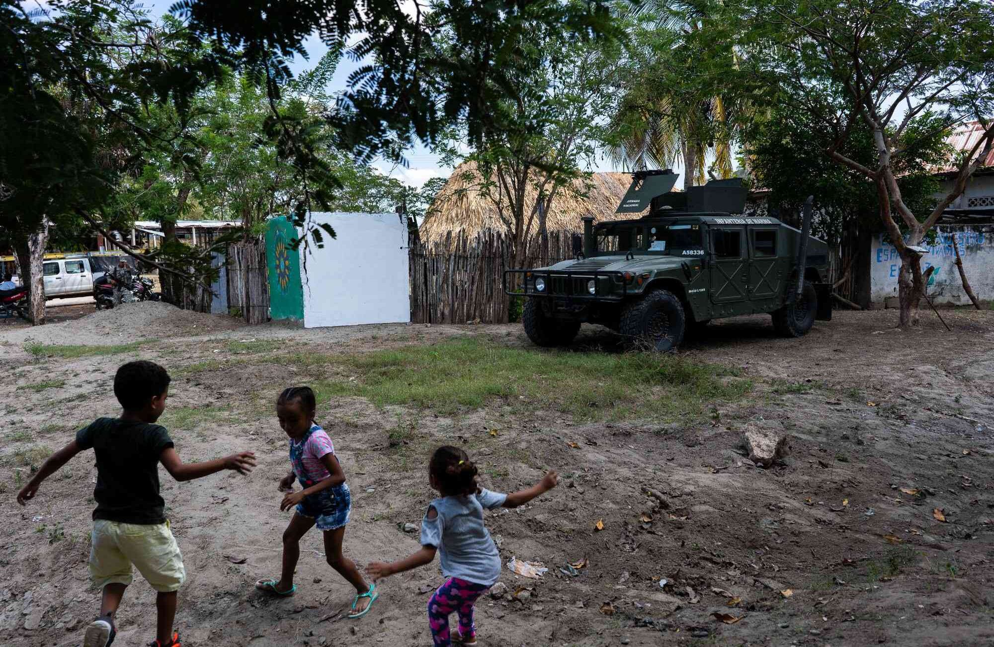 Un grupo de niños juega cerca de un convoy de la Infantería de Marina que hace presencia en El salado después de la orden del presidente Ivan Duque de aumentar el pie de fuerza en esta población a causa de las  recientes amenazas en contra de los lideres sociales.