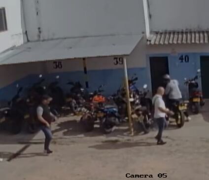 El ladrón de camisa negra persigue a su víctima de camiseta blanca que se encuentra caminando.