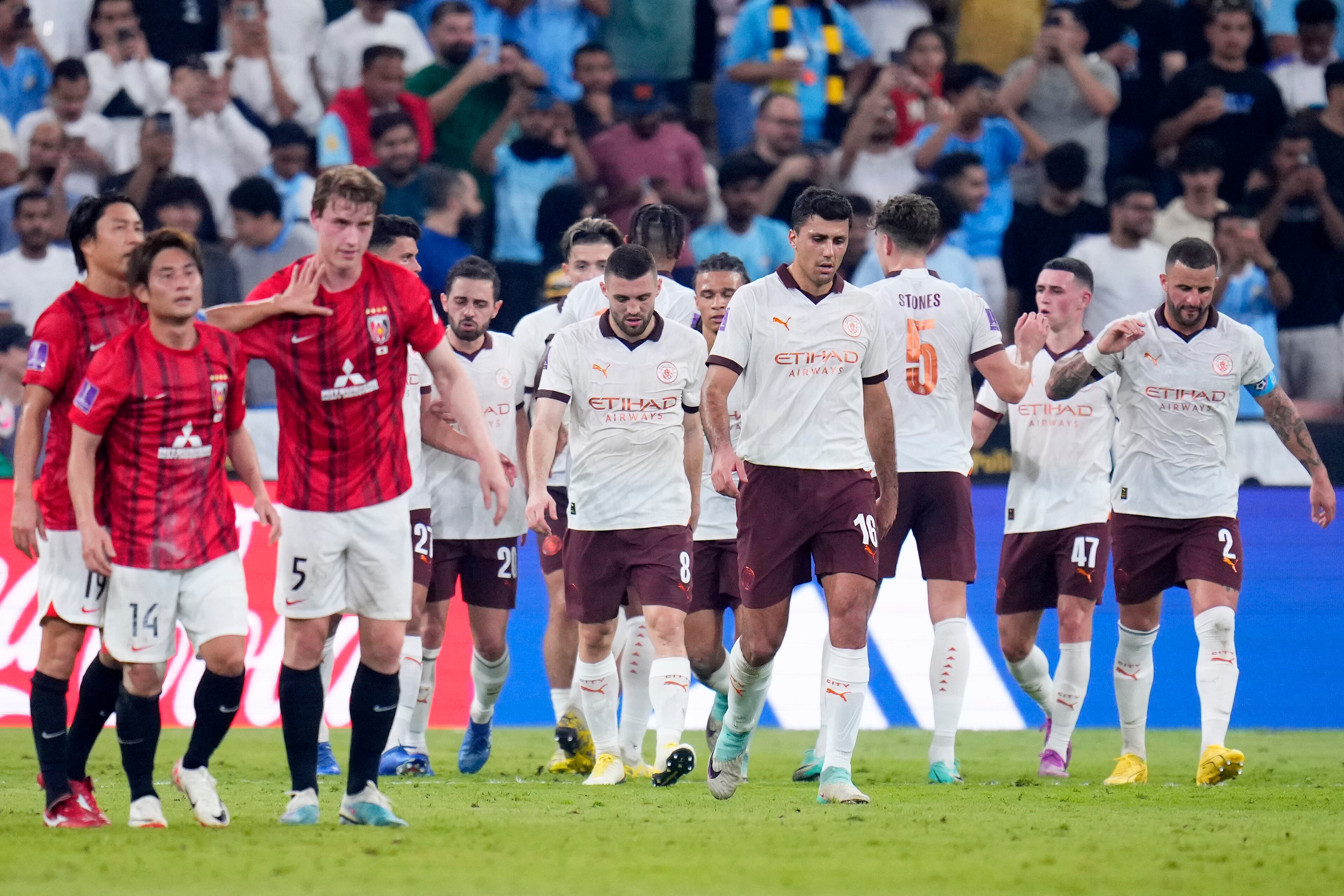 Manchester City players celebrate after Urawa Reds' Marius Hoibraten, 3rd left, scored an own goal to open the score during the Soccer Club World Cup semifinal soccer match between Urawa Reds and Manchester City FC at King Abdullah Sports City Stadium in Jeddah, Saudi Arabia, Tuesday, Dec. 19, 2023. (AP Photo/Manu Fernandez)