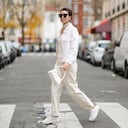 PARIS, FRANCE - DECEMBER 11: Katie Giorgadze @katie.one wears sunglasses, silver earrings, a beige / white latte braided wool zipper turtleneck / cut-out chest pullover, a white felt / wool zipper jacket, a white leather crocodile print pattern handbag, white latte denim jeans large pants, white leather embossed LV monogram print pattern sneakers from Louis Vuitton, during a street style fashion photo session, on December 11, 2021 in Paris, France. (Photo by Edward Berthelot/Getty Images)