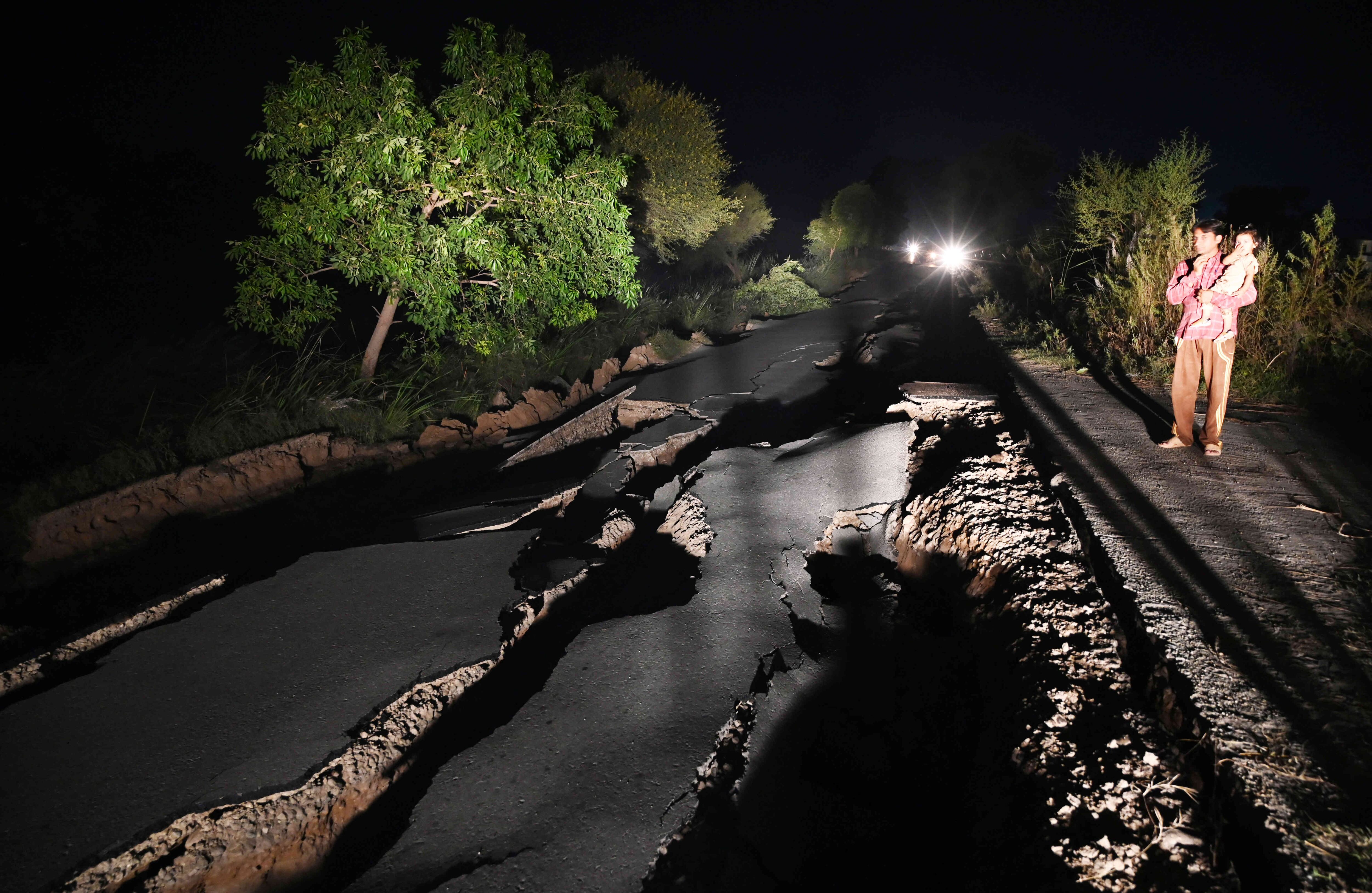 A las afueras de Mirpur, al norte de Pakistán, una carretera se abrió y agujeró completamente, después del terremoto. Los nativos miran asombrados sin poder salir del lugar. Foto: AFP/AAMIR QURESHI.