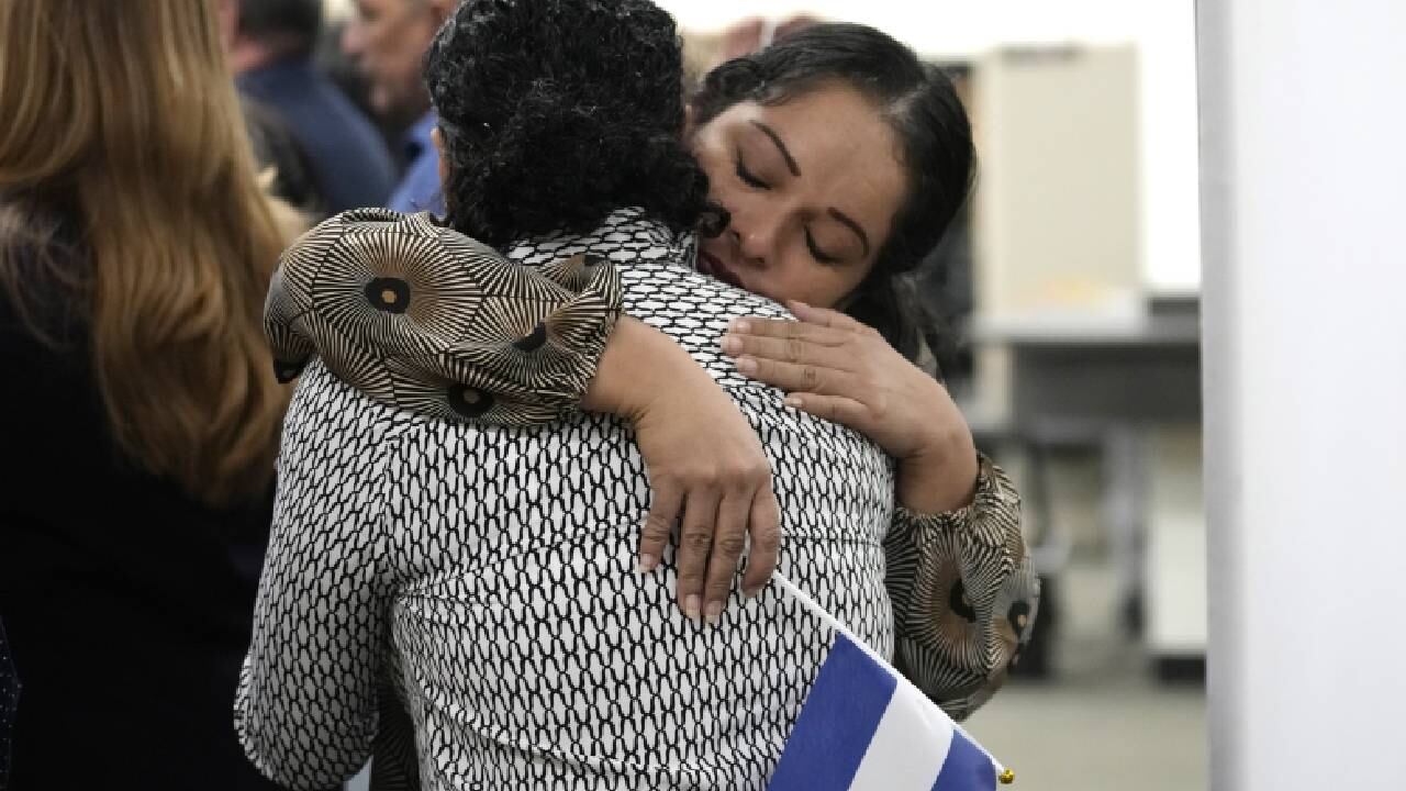 María José Aragón sostiene una bandera nicaragüense mientras abraza a María José Martínez, ambas prisioneras políticas recientemente liberadas de Nicaragua.