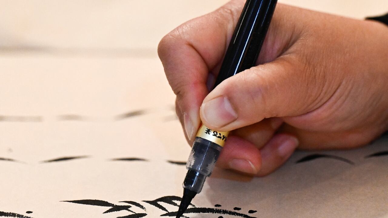 Esta fotografía, tomada el 14 de abril de 2025, muestra a la maestra Xu Yan escribiendo caracteres Nushu durante un taller en Pekín. El Nushu, "escritura femenina", se creó hace unos 400 años, cuando las mujeres aún tenían prohibido asistir a la escuela. Aprendieron en secreto caracteres chinos y los adaptaron al Nushu, utilizando la escritura para comunicarse entre sí mediante cartas, canciones y bordados. Foto: Pedro PARDO / AFP.