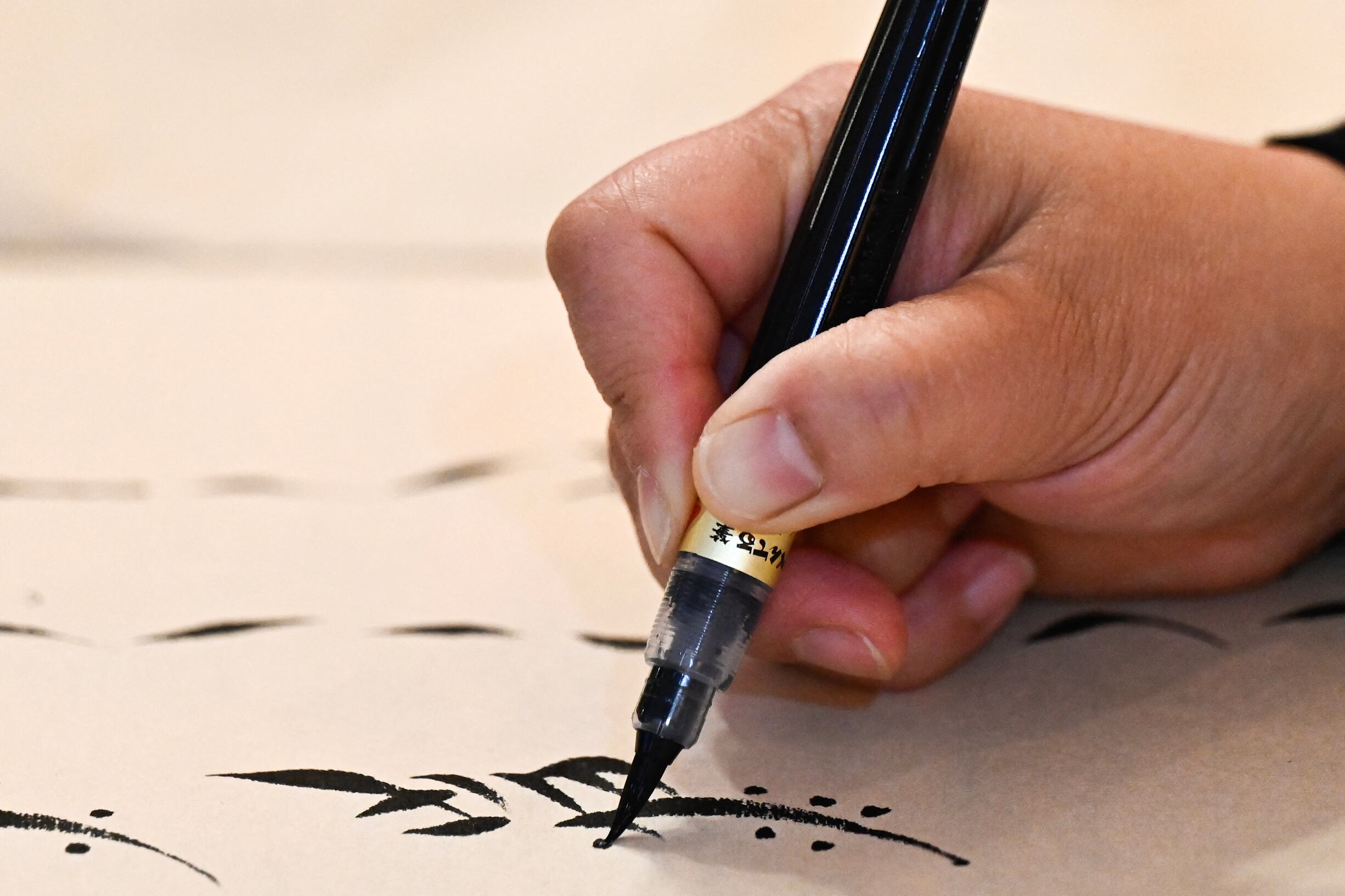 Esta fotografía, tomada el 14 de abril de 2025, muestra a la maestra Xu Yan escribiendo caracteres Nushu durante un taller en Pekín. El Nushu, "escritura femenina", se creó hace unos 400 años, cuando las mujeres aún tenían prohibido asistir a la escuela. Aprendieron en secreto caracteres chinos y los adaptaron al Nushu, utilizando la escritura para comunicarse entre sí mediante cartas, canciones y bordados. Foto: Pedro PARDO / AFP.