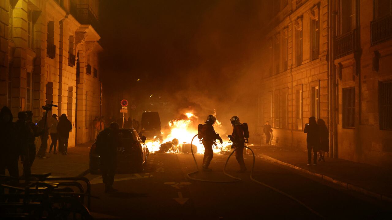 Los bomberos franceses (C) operan en un incendio durante una manifestación cerca de la Place de la Concorde después de que el gobierno francés impulsara una reforma de las pensiones en el parlamento sin votación, utilizando el artículo 49,3 de la constitución, en París el 16 de marzo de 2023. - El 16 de marzo, el presidente francés impuso una controvertida reforma de pensiones en el parlamento sin votación, desplegando un poder constitucional rara vez utilizado que corre el riesgo de inflamar las protestas. La medida fue una admisión de que su gobierno carecía de una mayoría en la Asamblea Nacional para aprobar la legislación para aumentar la edad de jubilación de 62 a 64 años. (Foto de Thomas SAMSON / AFP)