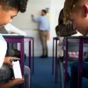 Jovenes revisan su celular en una aula de clase. Imagen de referencia