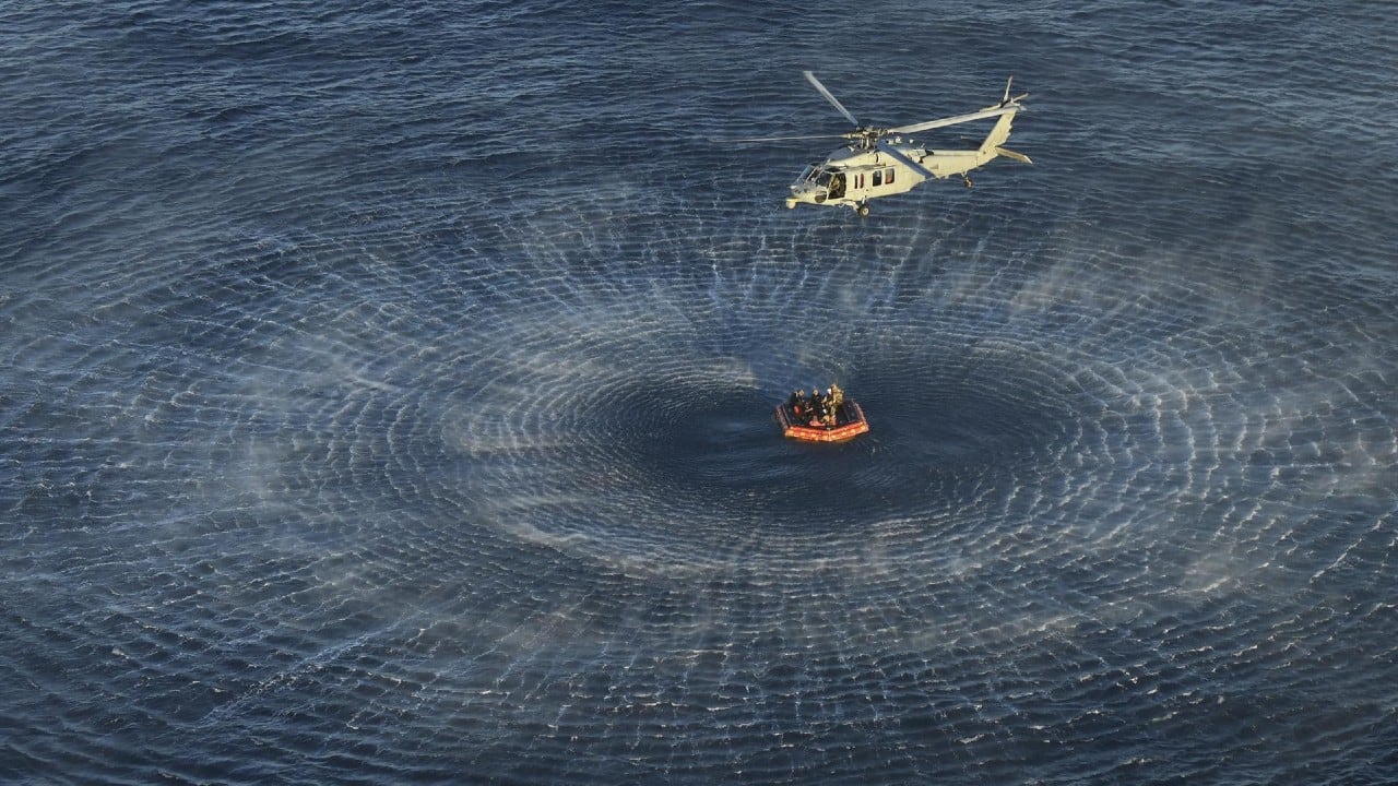 Momento en que los buzos de la Marina de los EE. UU. y los astronautas de Artemis II a bordo de una balsa inflable son abordados por helicópteros y llevados a la nave de recuperación.