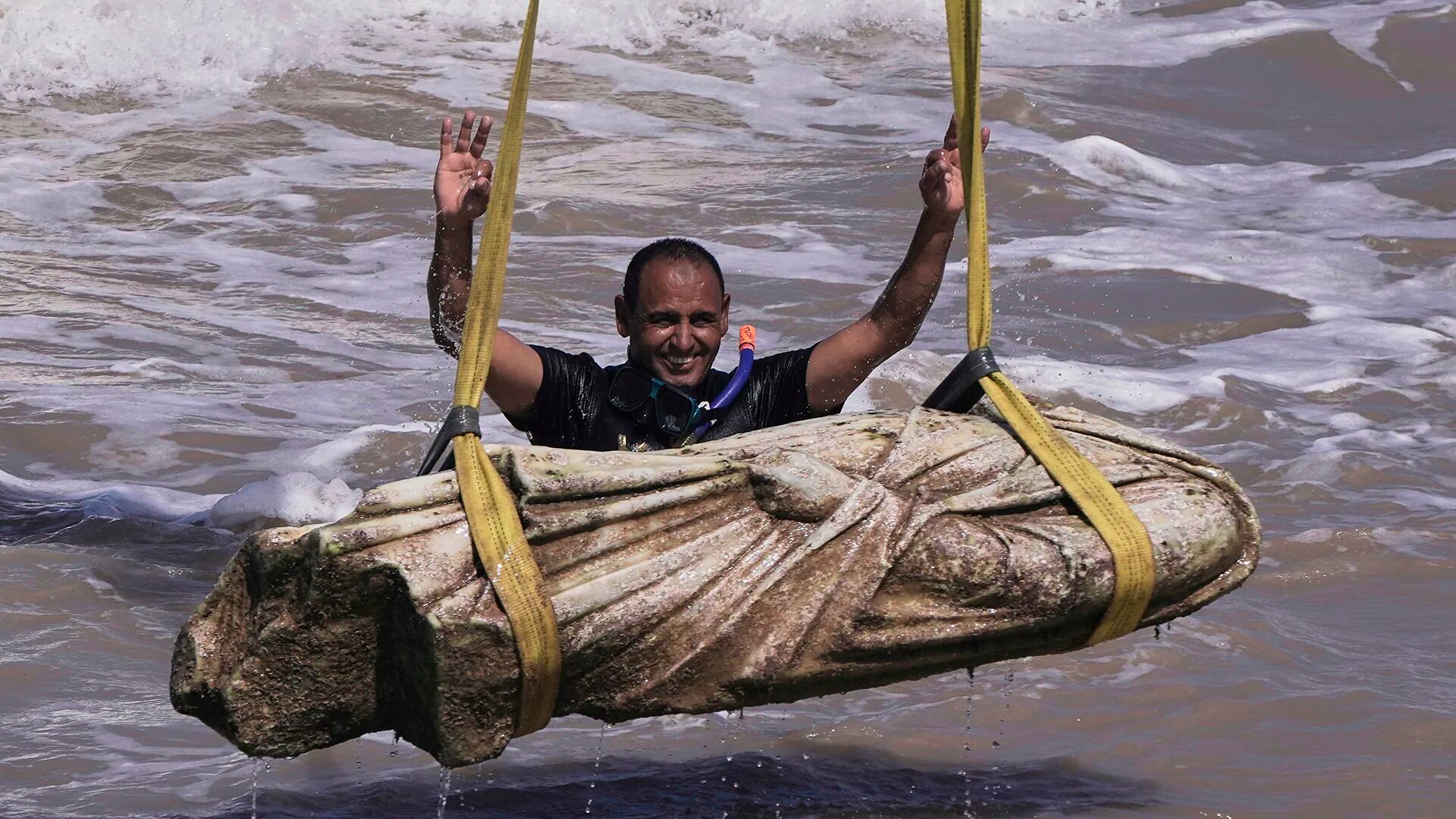 Un buceador celebra después de que se levantara una de las reliquias antiguas del agua en la bahía de Abu Qir, en la ciudad de Alejandría, Egipto, el jueves 21 de agosto de 2025.