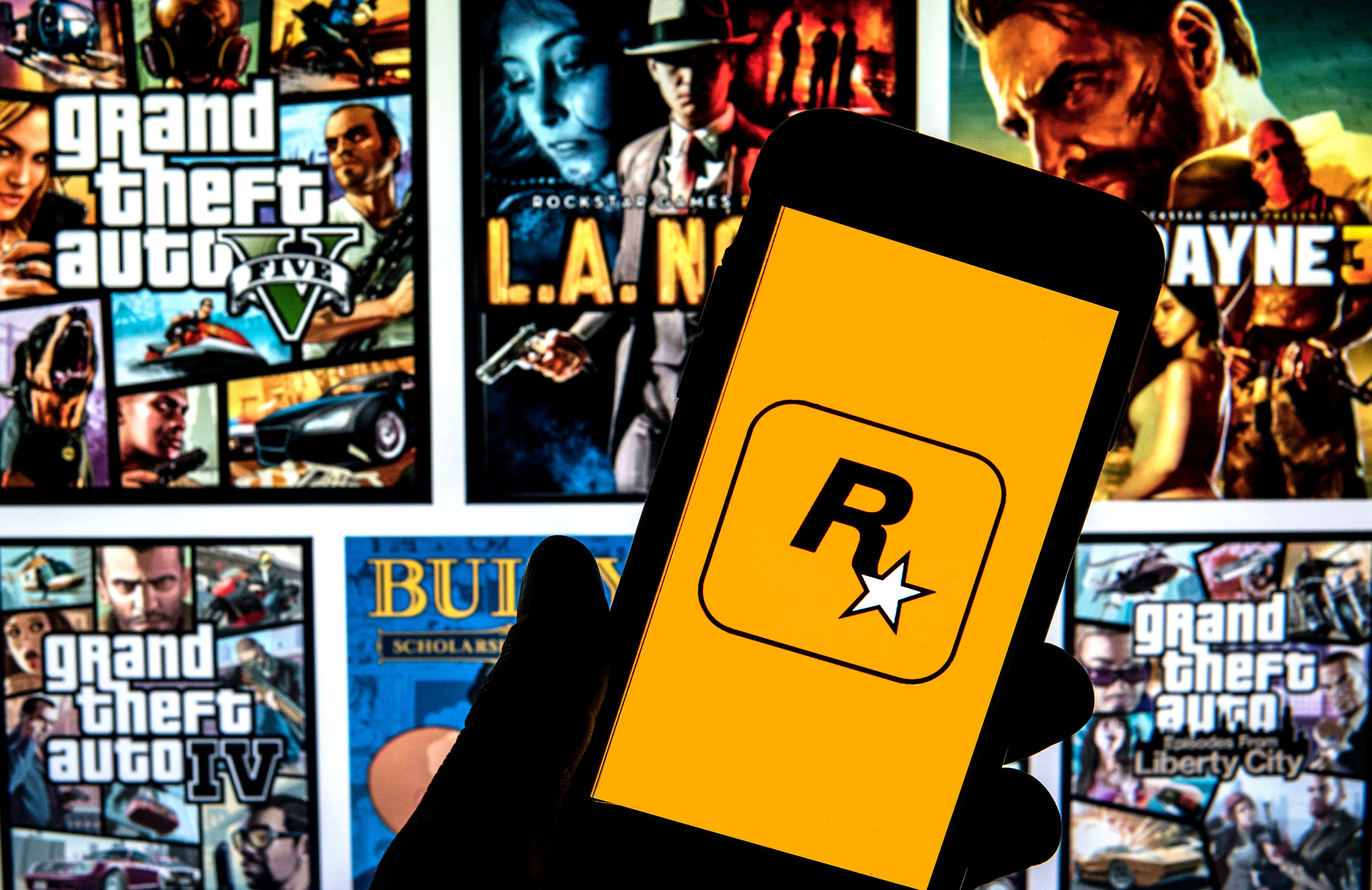 En esta ilustración fotográfica se muestra el logotipo de Rockstar Games en un teléfono inteligente con la portada de un videojuego de fondo.