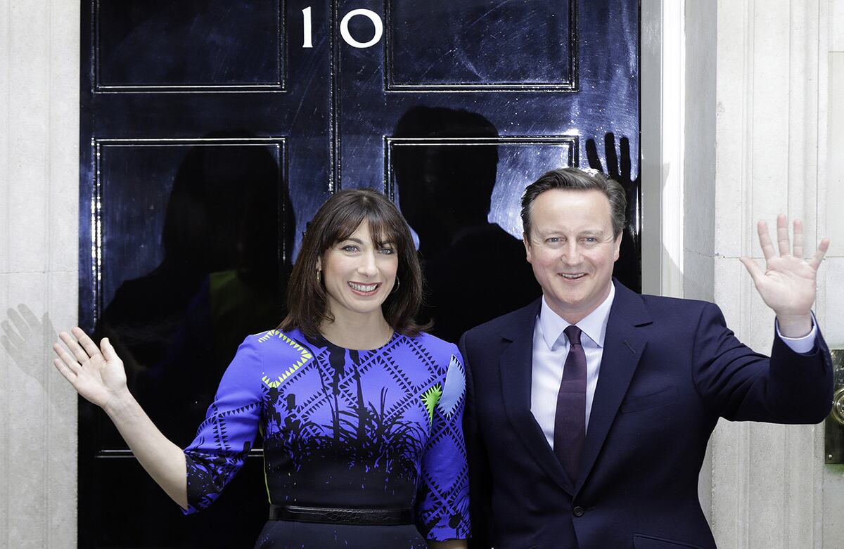 El primer ministro británico, David Cameron y su esposa Samanta saludan luego de encontrarse con la reina Isabel II para contarle que cuenta con el apoyo suficiente para conformar un gobierno. (AP/Alastair Grant)