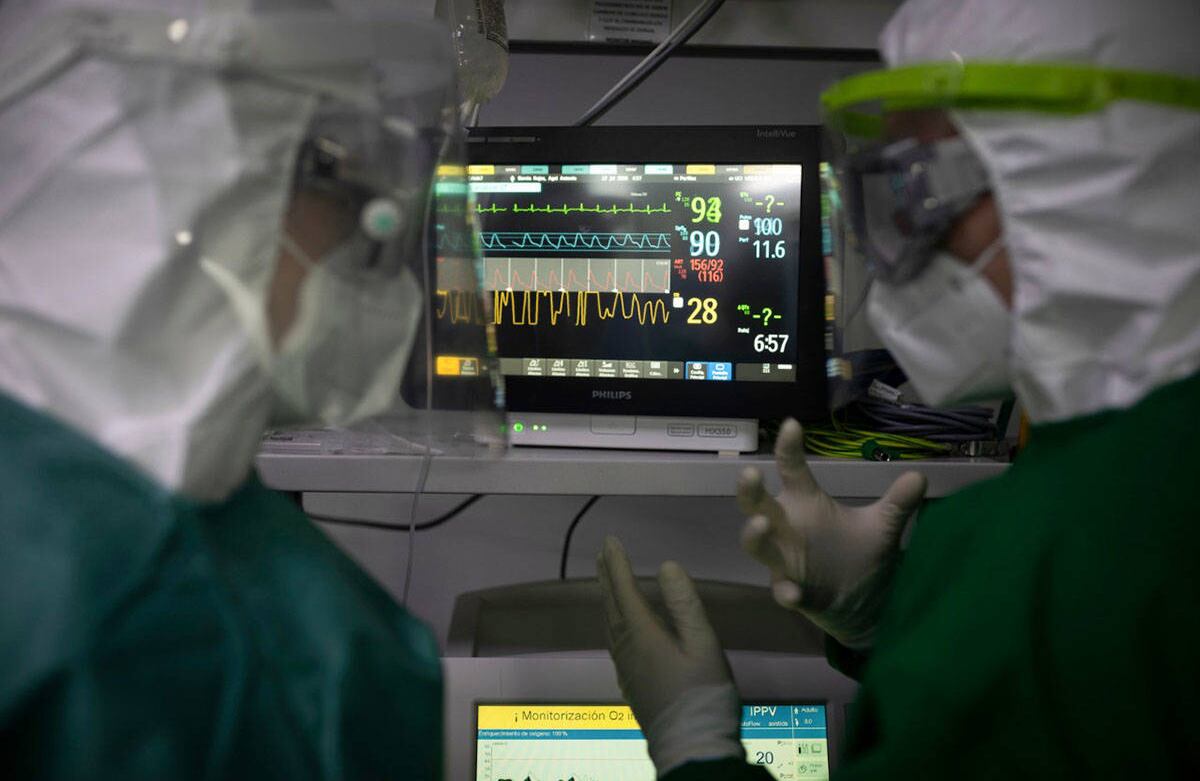 Dos profesionales de la salud monitoreando los signos vitales de un paciente internado en una UCI/ Foto: Esteban Vega/ SEMANA