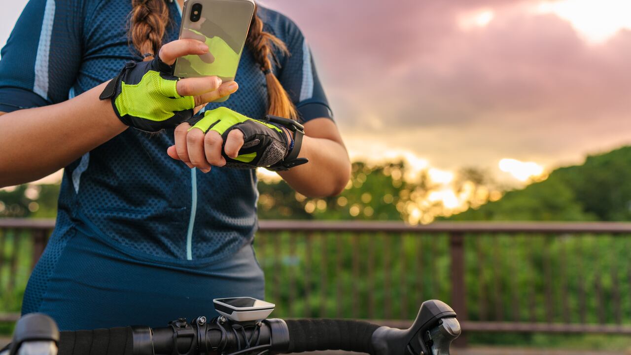 Una ciclista está configurando su reloj inteligente y su teléfono inteligente antes de andar en bicicleta.