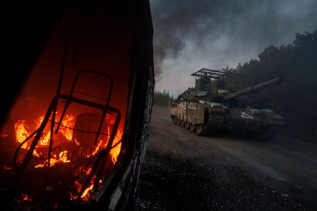 ARCHIVO - Un tanque ucraniano pasa junto a un automóvil en llamas en la región de Sumy el 14 de agosto de 2024, en Ucrania, cerca de la frontera con Rusia. (AP Foto/Evgeniy Maloletka, archivo)