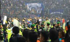 MALANG, INDONESIA - OCTOBER 01: Football supporters enter the pitch as security officers try to disperse them during a riot following a soccer match at Kanjuruhan Stadium in Malang, East Java, Indonesia, 01 October 2022. According to government officials, at least 174 people including police officers were killed mostly in stampedes after riots following a soccer match. (Photo by Getty Images/Suryanto/Anadolu Agency)