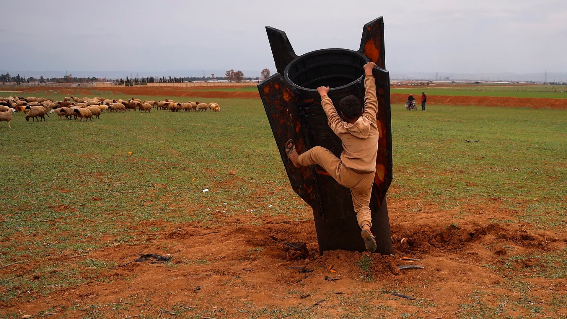 Exponiéndose al peligro de munición sin explotar, un niño intenta subirse a un proyectil iraní que aterrizó en un campo abierto en las afueras de Qamishli, al este de Siria, el miércoles 4 de marzo de 2026.