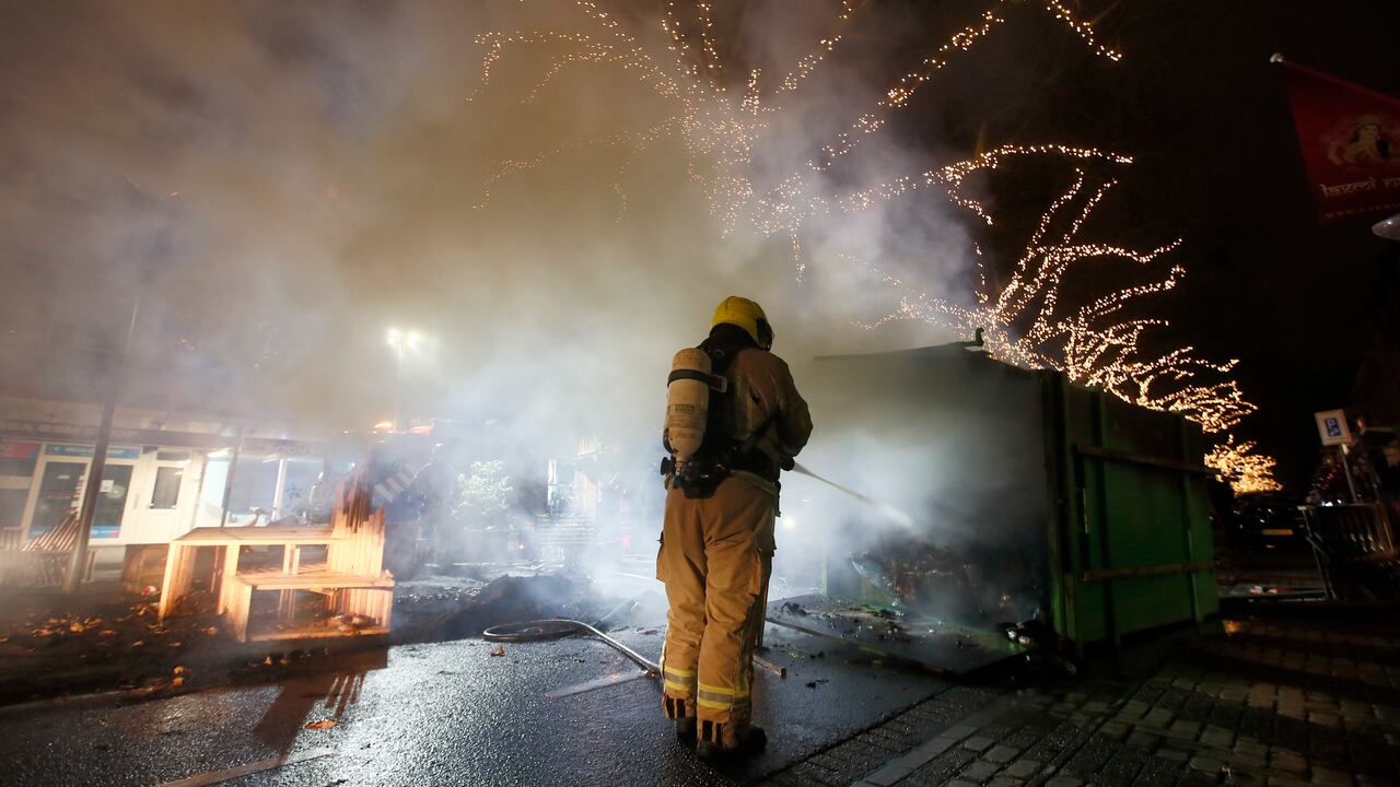 A firefighter extinguishes a a container that was set alight during protests against a nation-wide curfew in Rotterdam, Netherlands, Monday, Jan. 25, 2021. The Netherlands Saturday entered its toughest phase of anti-coronavirus restrictions to date, imposing a nationwide night-time curfew from 9 p.m. until 4:30 a.m. in a bid to control the COVID-19 infection rate. (AP Photo/Peter Dejong)