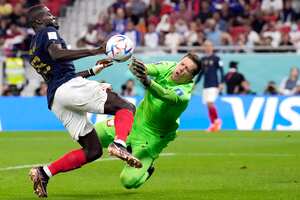 El francés Dayot Upamecano, a la izquierda, intenta marcar un gol mientras el portero polaco Wojciech Szczesny, a la derecha, defiende durante el partido de fútbol de octavos de final de la Copa Mundial entre Francia y Polonia, en el Estadio Al Thumama en Doha, Qatar, el domingo 4 de diciembre 2022.