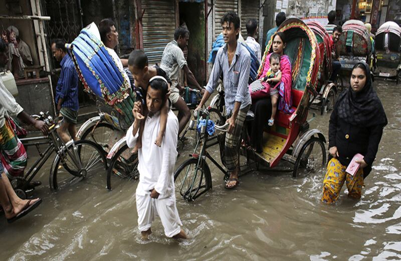 Personas circulan por una calle inundada de Dacca en Bangladés.