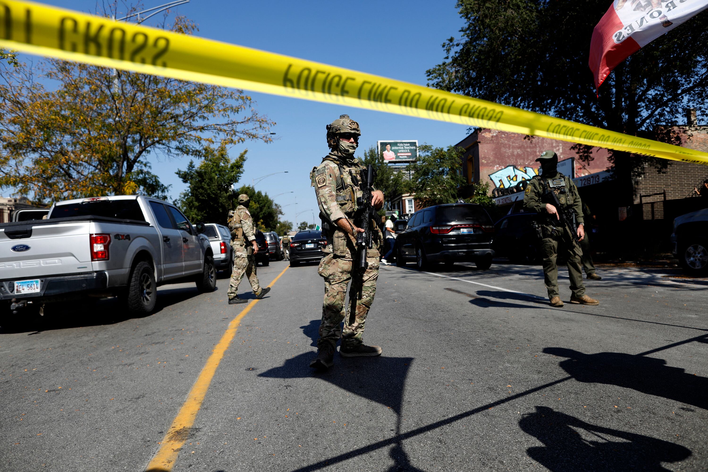 Masked US Customs and Border Protection (CBP) Border Patrol agents stand behind a police line as residents of Chicago's Brighton Park neighborhood confront law enforcement at a gas station after Immigration and Customs Enforcement (ICE) agents allegedly detained an unidentified man riding in his car, in Chicago, Illinois, on October 4, 2025. US President Donald Trump, who campaigned on a pledge to deport large numbers of migrants, has encouraged authorities to be more aggressive as he seeks to hit his widely reported target of one million deportations annually. (Photo by OCTAVIO JONES / AFP)