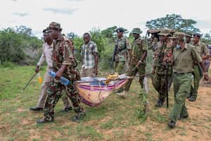 Agentes de la policía y residentes cargan los cuerpos exhumados de víctimas de una secta religiosa, en la localidad de Shakahola, cerca de la ciudad costera de Malindi, en el sur de Kenia, el domingo 23 de abril de 2023. (AP Foto)