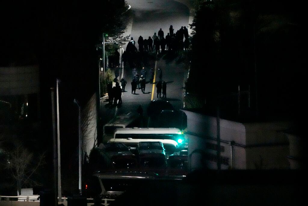 El personal de seguridad se reúne detrás de los autobuses que bloquean la puerta de entrada de la residencia del presidente surcoreano acusado Yoon Suk Yeol en Seúl, Corea del Sur, el miércoles 15 de enero de 2025. (Foto AP/Ahn Young-joon)