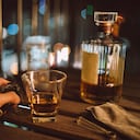 First person view of a man enjoying a glass of whisky and a smoking pipe on the balcony at night