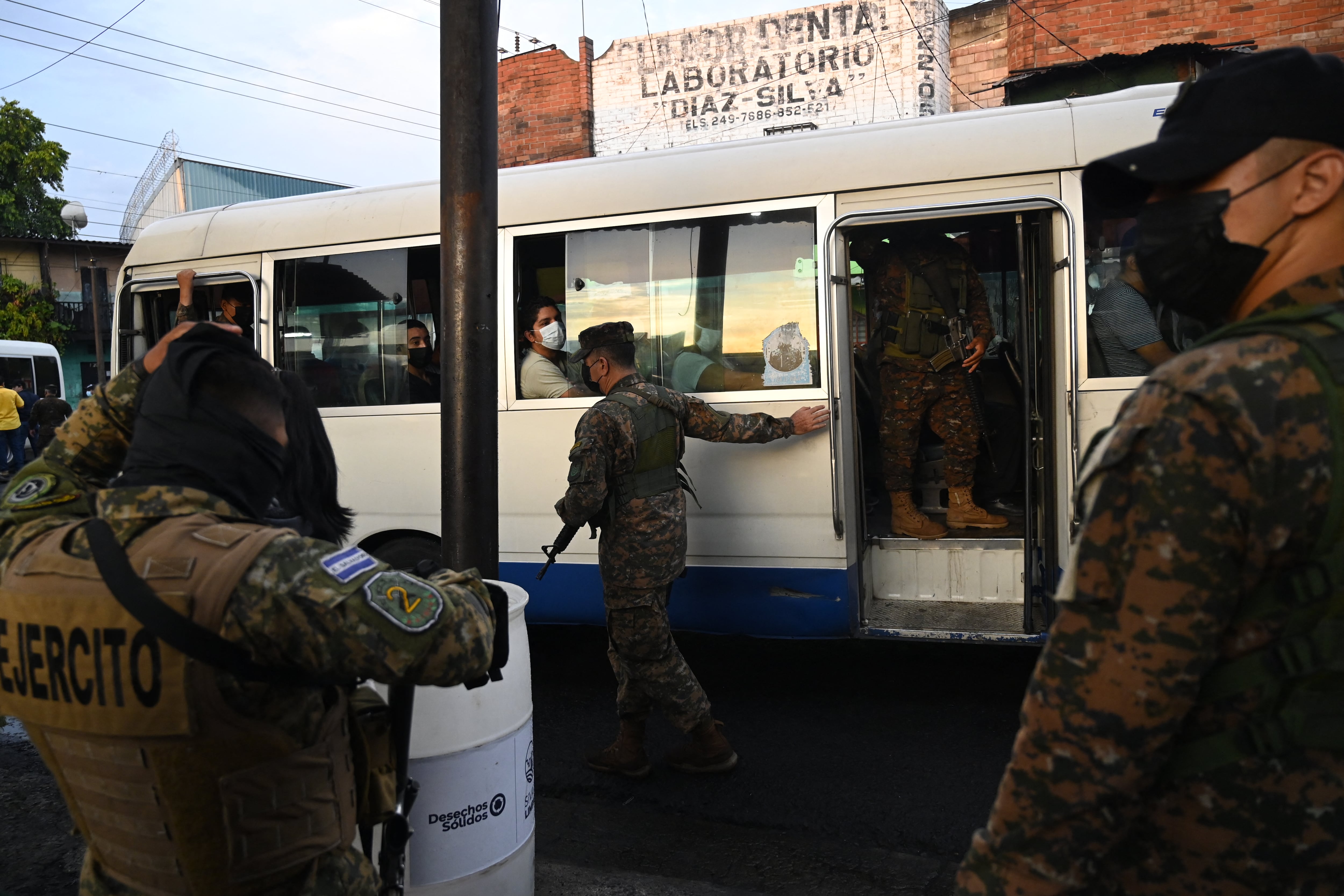 Soldiers escort a public transport bus in San Salvador on March 16, 2022. - The government intervened two routes of collective transport after the illegal increase in the cost of the ticket by now captured transport entrepreneur Catalino Miranda, who is also charged with the crimes of resistance and public disorder. (Photo by MARVIN RECINOS / AFP)