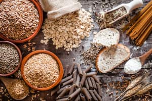 Top view of wholegrain and cereal composition shot on rustic wooden table. This type of food is rich of fiber and is ideal for dieting. The composition includes wholegrain sliced bread, various kinds of wholegrain pasta, wholegrain crackers, grissini, oat flakes, brown rice, spelt and flax seeds. Predominant color is brown. DSRL studio photo taken with Canon EOS 5D Mk II and Canon EF 100mm f/2.8L Macro IS USM