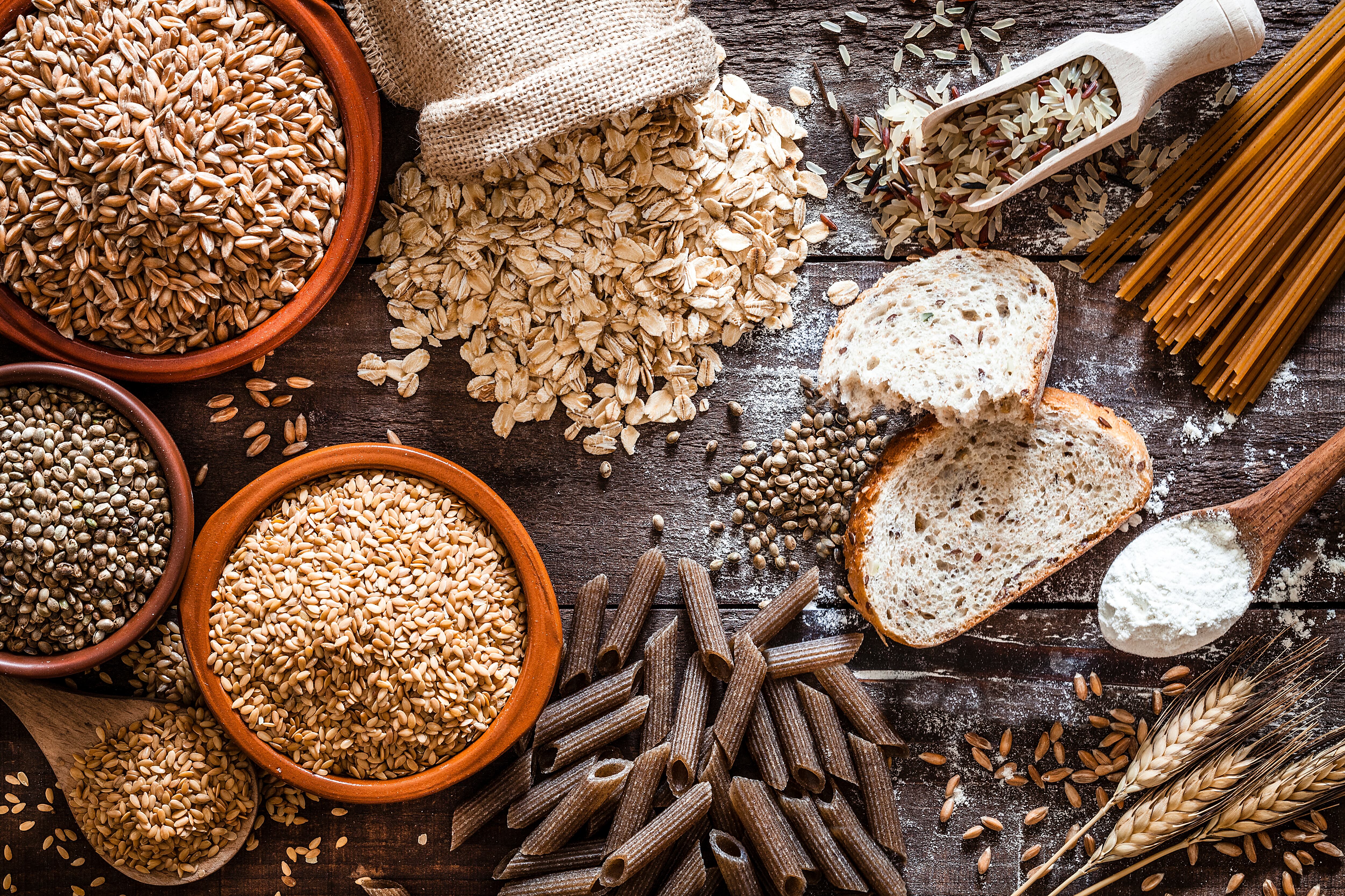 Top view of wholegrain and cereal composition shot on rustic wooden table. This type of food is rich of fiber and is ideal for dieting. The composition includes wholegrain sliced bread, various kinds of wholegrain pasta, wholegrain crackers, grissini, oat flakes, brown rice, spelt and flax seeds. Predominant color is brown. DSRL studio photo taken with Canon EOS 5D Mk II and Canon EF 100mm f/2.8L Macro IS USM