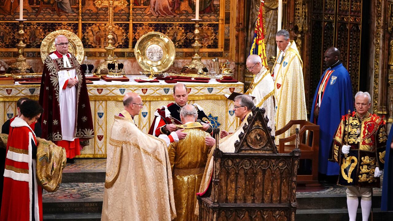 El príncipe William le pone una túnica al rey Carlos III durante su ceremonia de coronación en la Abadía de Westminster