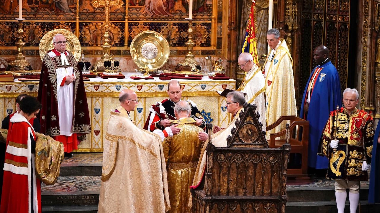El príncipe William le pone una túnica al rey Carlos III durante su ceremonia de coronación en la Abadía de Westminster