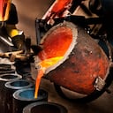 Trabajador vertiendo metal líquido en crisol.