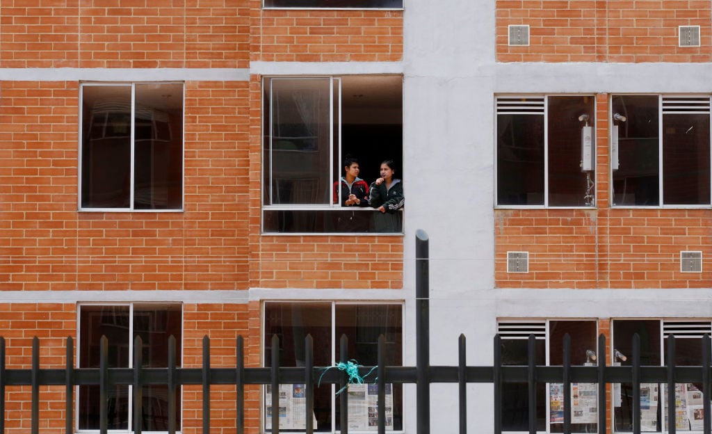 Dos mujeres miran desde una ventana en un complejo de apartamentos - Foto de referencia