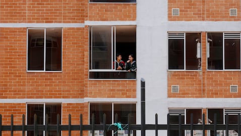 Dos mujeres miran desde una ventana en un complejo de apartamentos - Foto de referencia