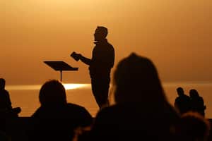 El pastor asociado de la Iglesia Park Community, Trevor Lovell, se recorta contra el cielo mientras dirige un servicio al amanecer de Pascua mientras los feligreses escuchan el domingo 4 de abril de 2021 en North Avenue Beach en Chicago. Foto: AP / Shafkat Anowar.