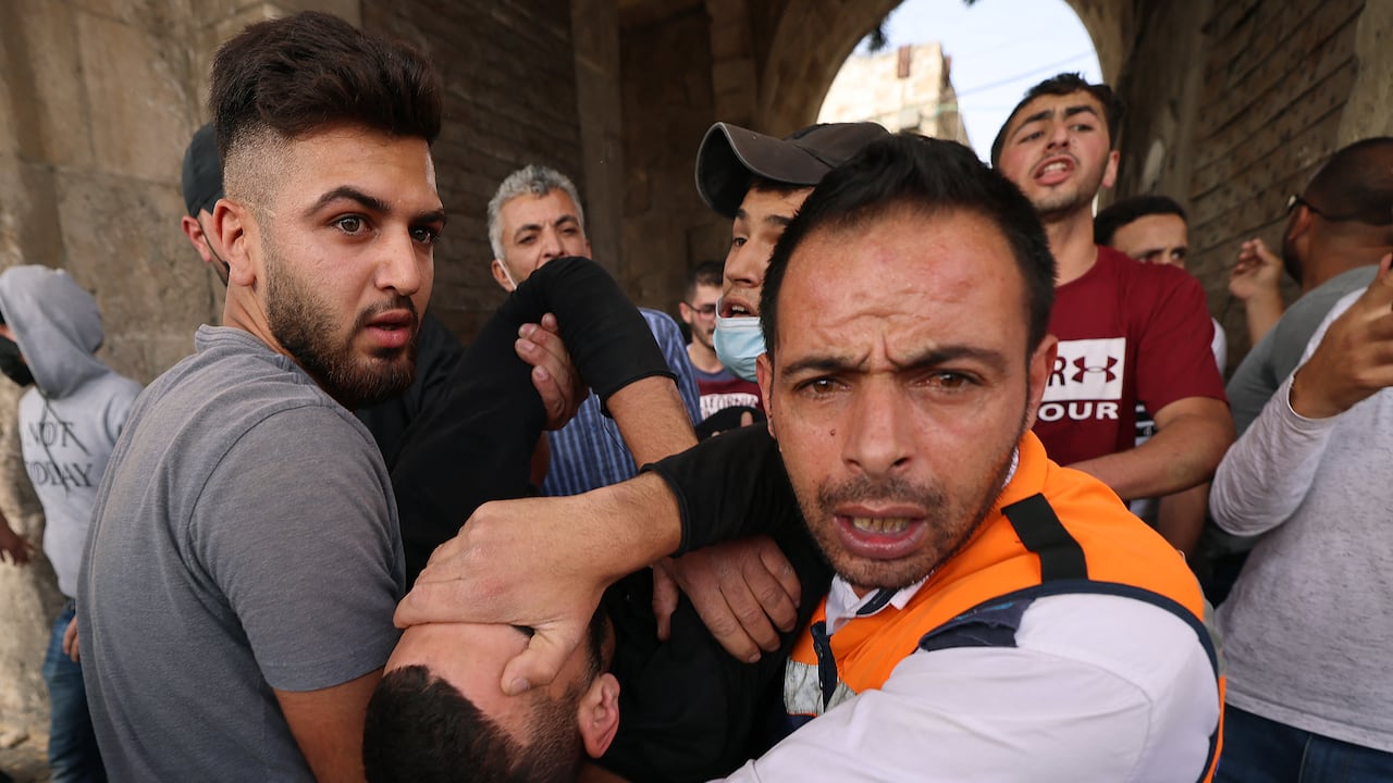 Médicos palestinos evacuan a un manifestante herido en medio de enfrentamientos con las fuerzas de seguridad israelíes en la Ciudad Vieja de Jerusalén el 10 de mayo de 2021, ya que una marcha planificada para marcar la toma de la ciudad santa por parte de Israel en 1967 amenazaba con inflamar aún más las tensiones. (Photo by EMMANUEL DUNAND / AFP)