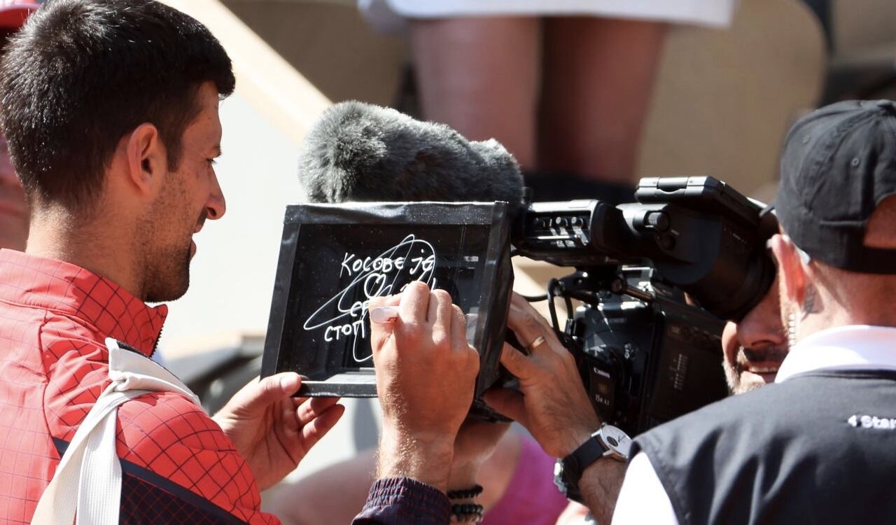 Momento en el Novak Djokovic escribe en una cámara el mensaje respecto a la situación que se vive en Kosovo.