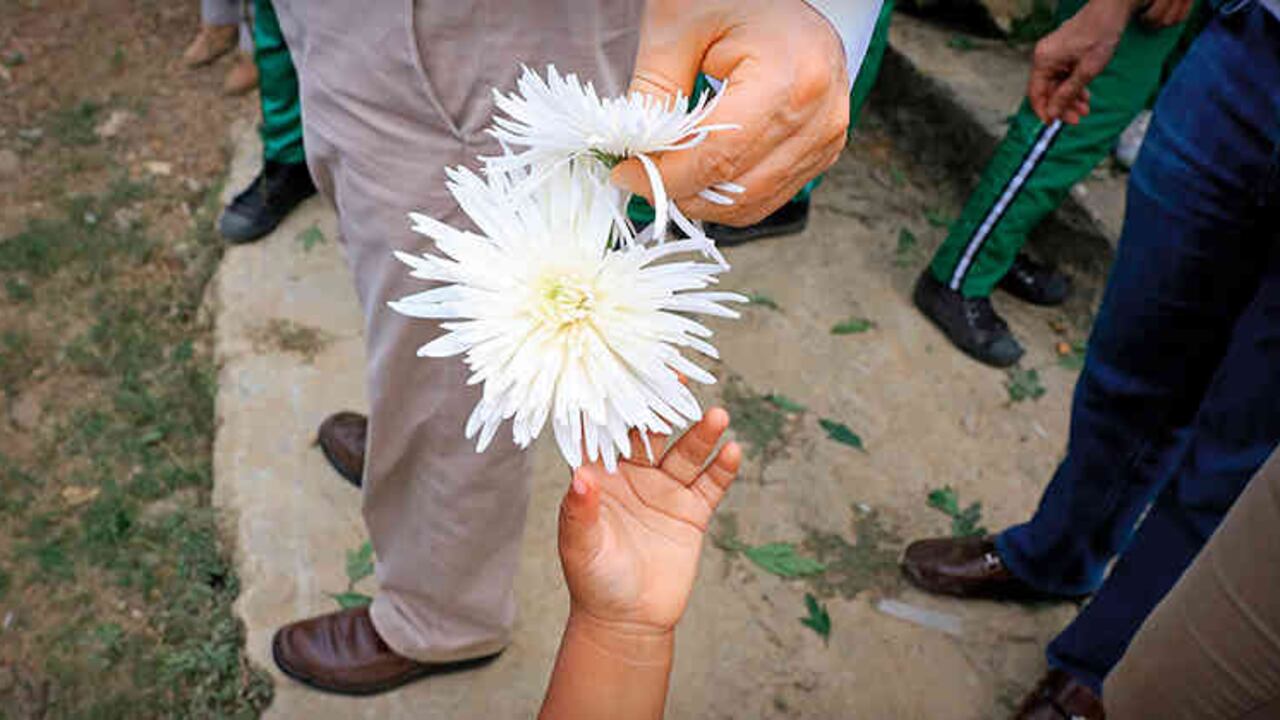 Un niño ofrece una flor al ministro del Interior Juan Fernando Cristo, en Machuca, el pasado 9 de abril.