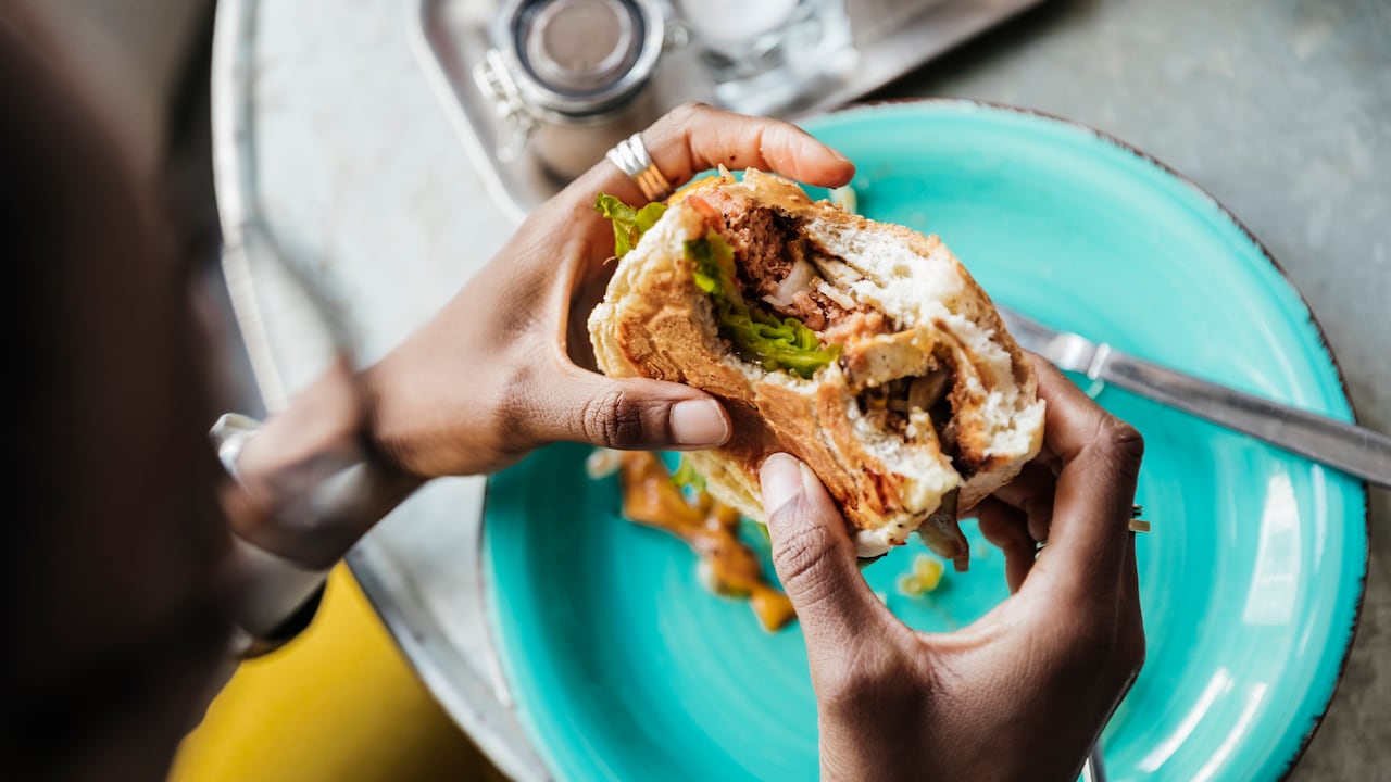 A close up of a woman eating a vegan meal in a local cafe with friends.