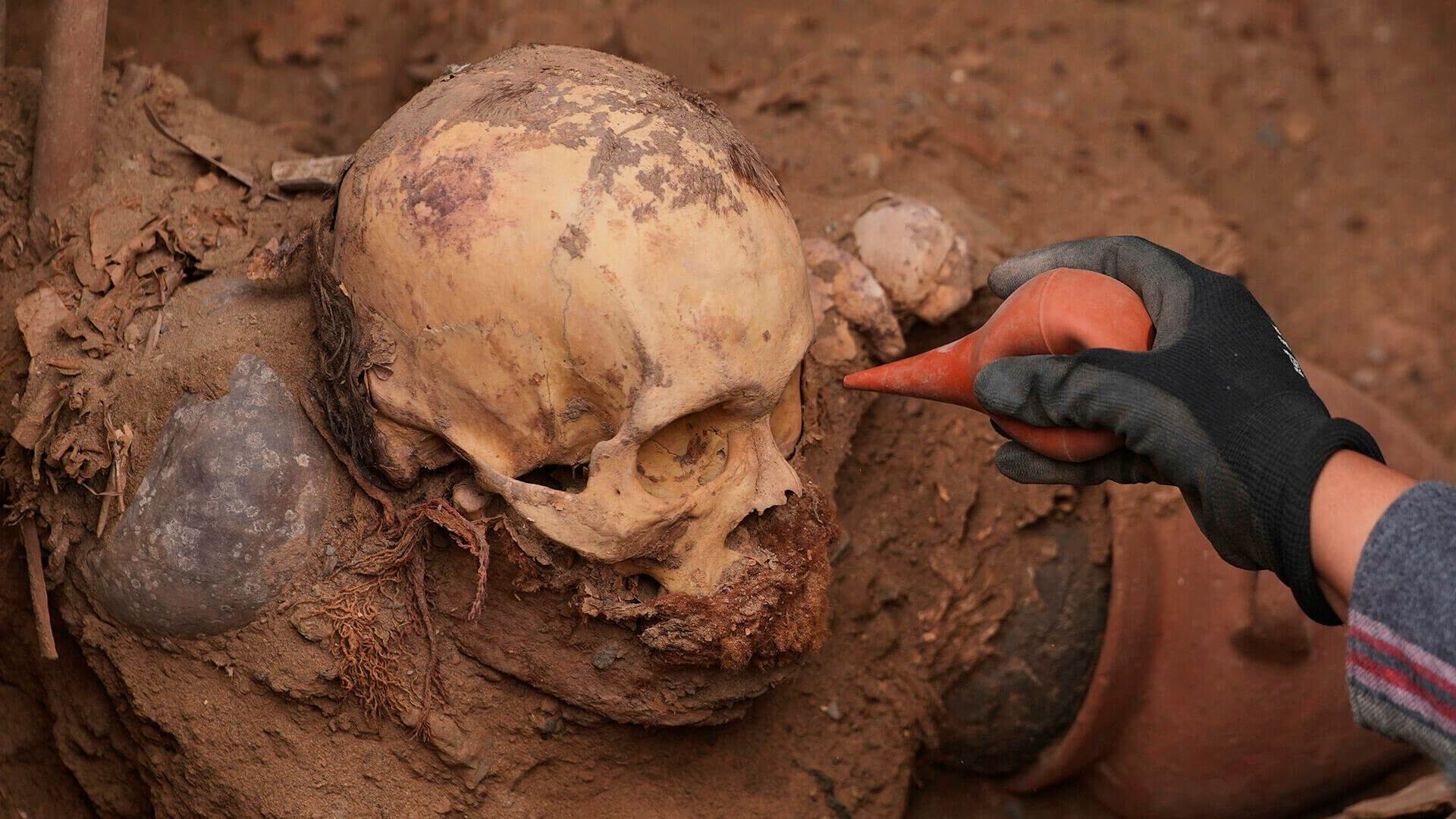 El arqueólogo José Aliaga trabaja en el lugar donde fueron hallados restos óseos, presuntamente de la cultura preincaica Chancay, durante la excavación de una línea de gas natural en Puente Piedra, Lima, Perú, el jueves 31 de julio de 2025.