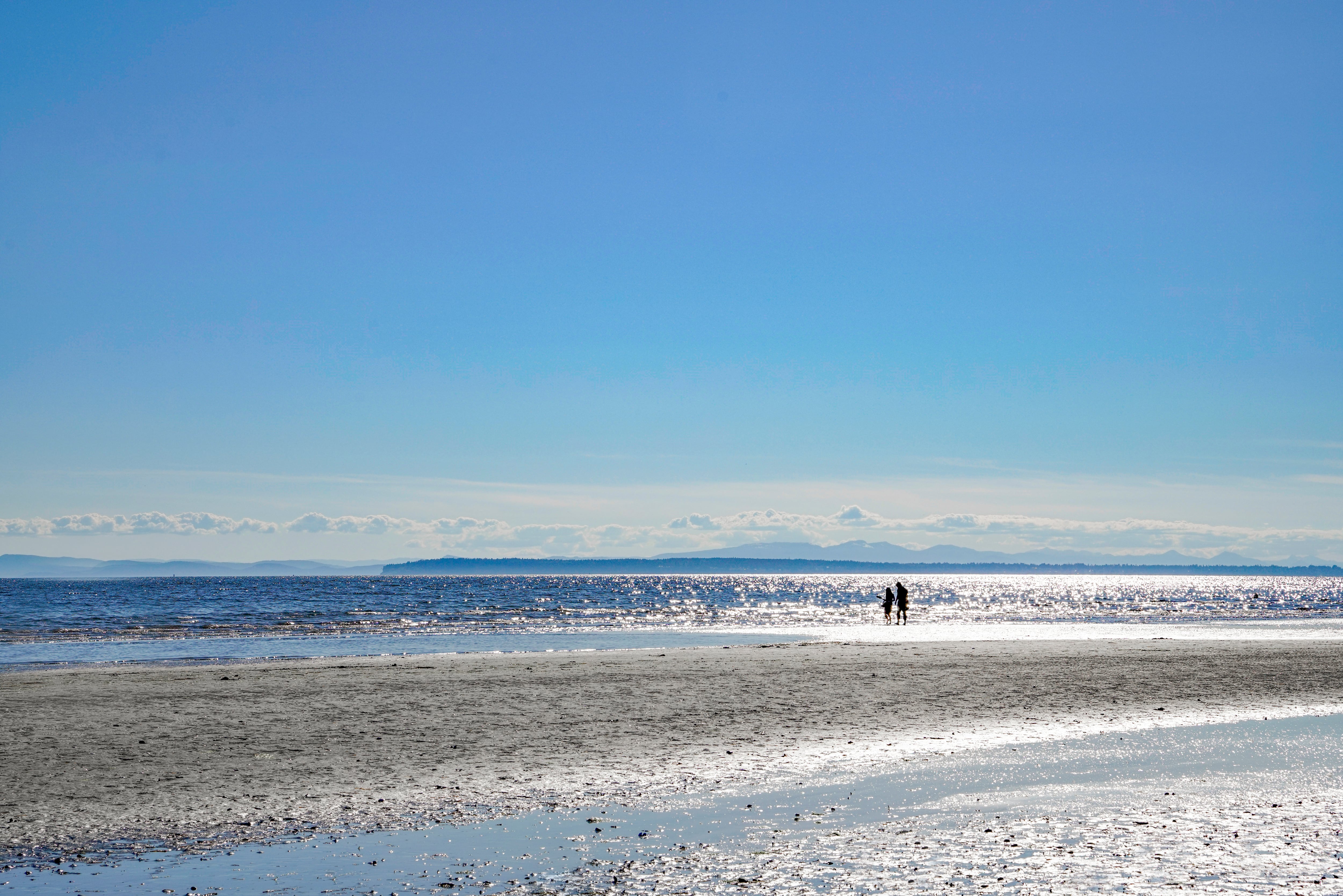 Young couple walking on beach in a sunny day.