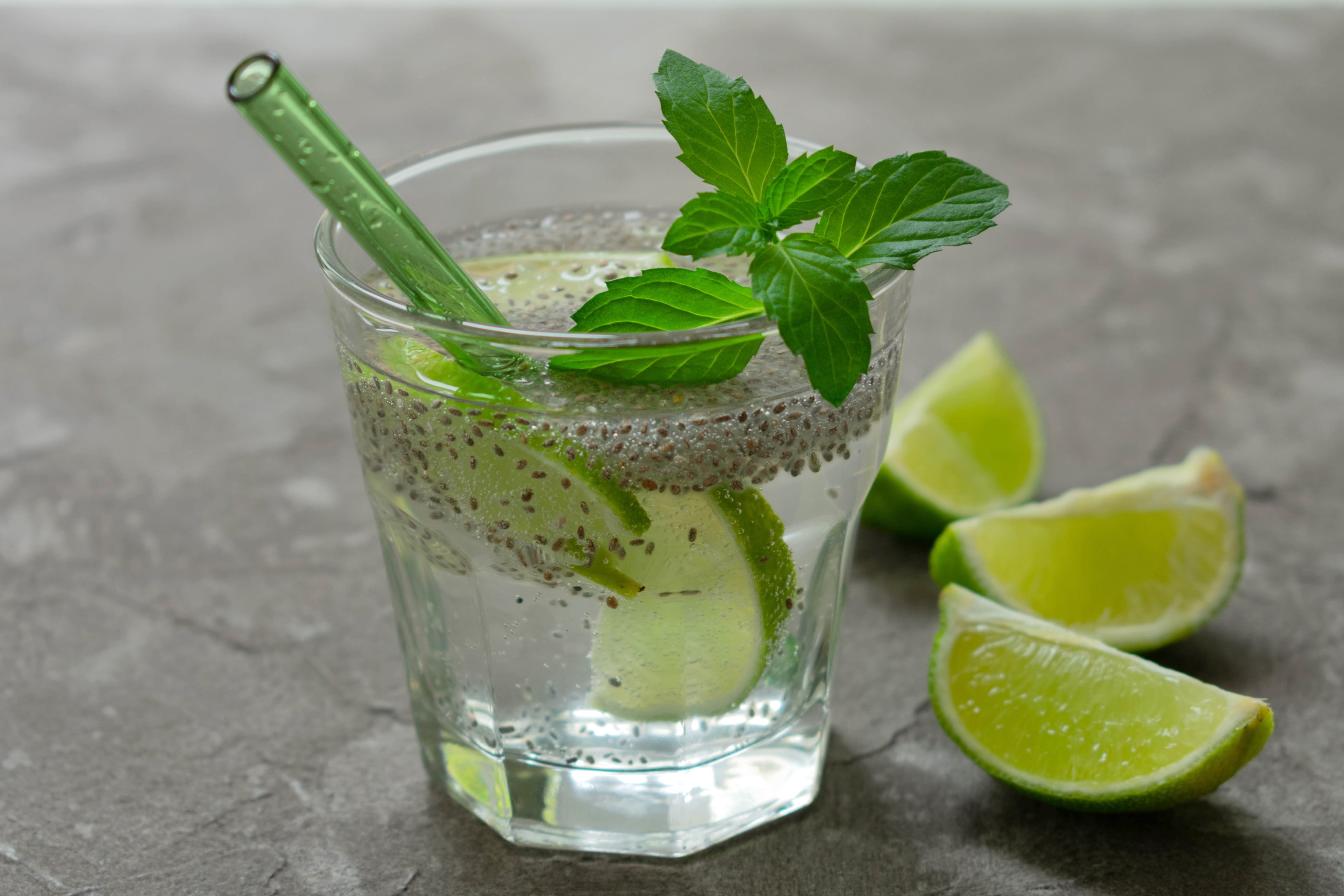 Glass of water with chia seeds and lime on a gray background. A healthy drink for weight loss.